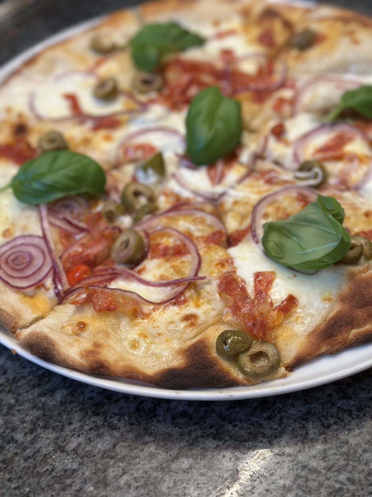 Pizza mit Basilikum, Oliven und Zwiebeln